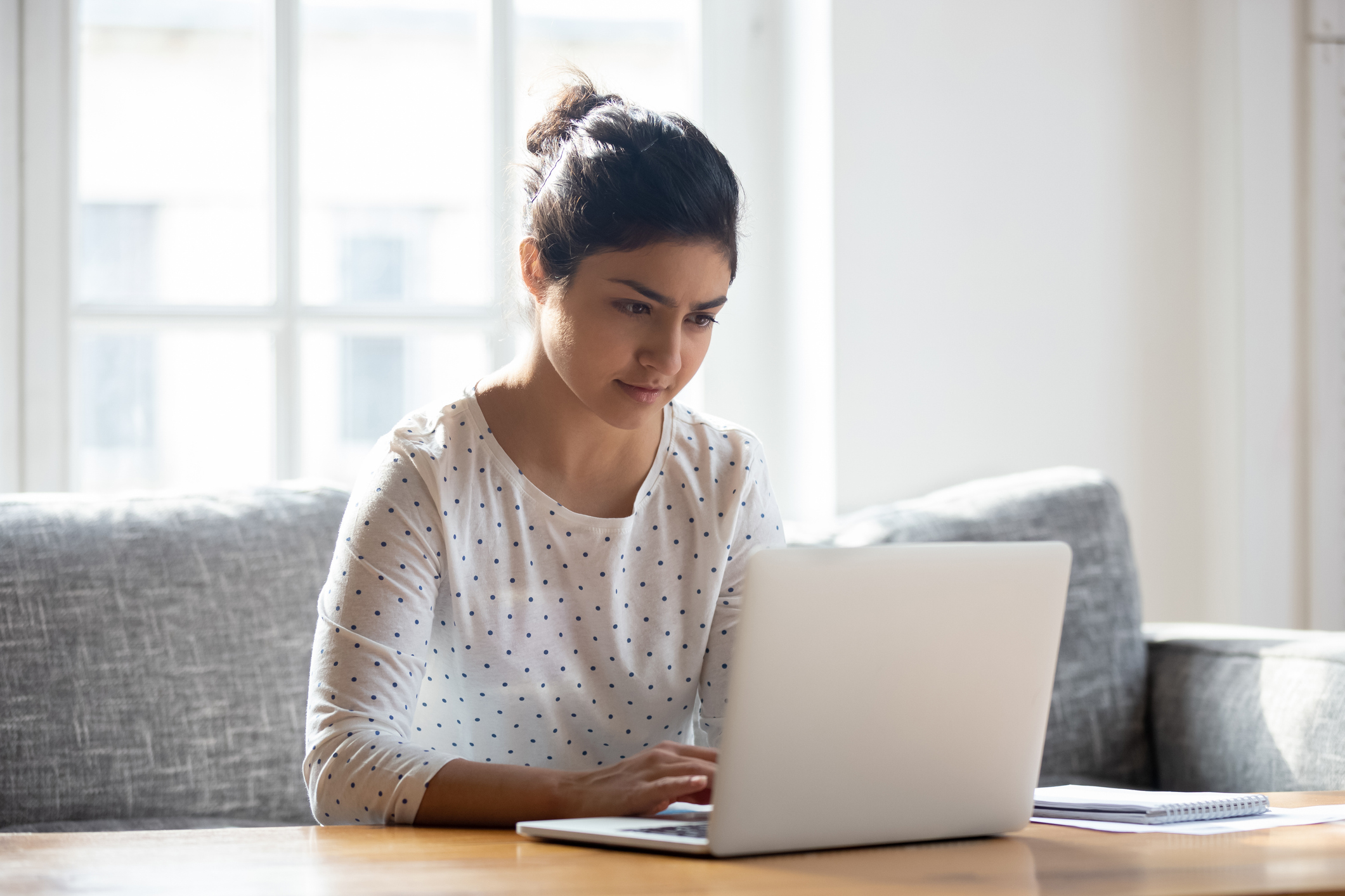 A lady sitting at a table using a laptop, searching for interest-only mortgages