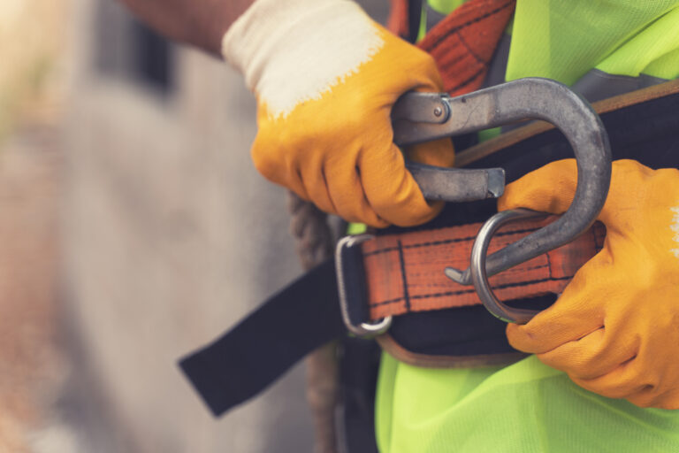 Construction working attaching safety harness belt, ensuring correct protection